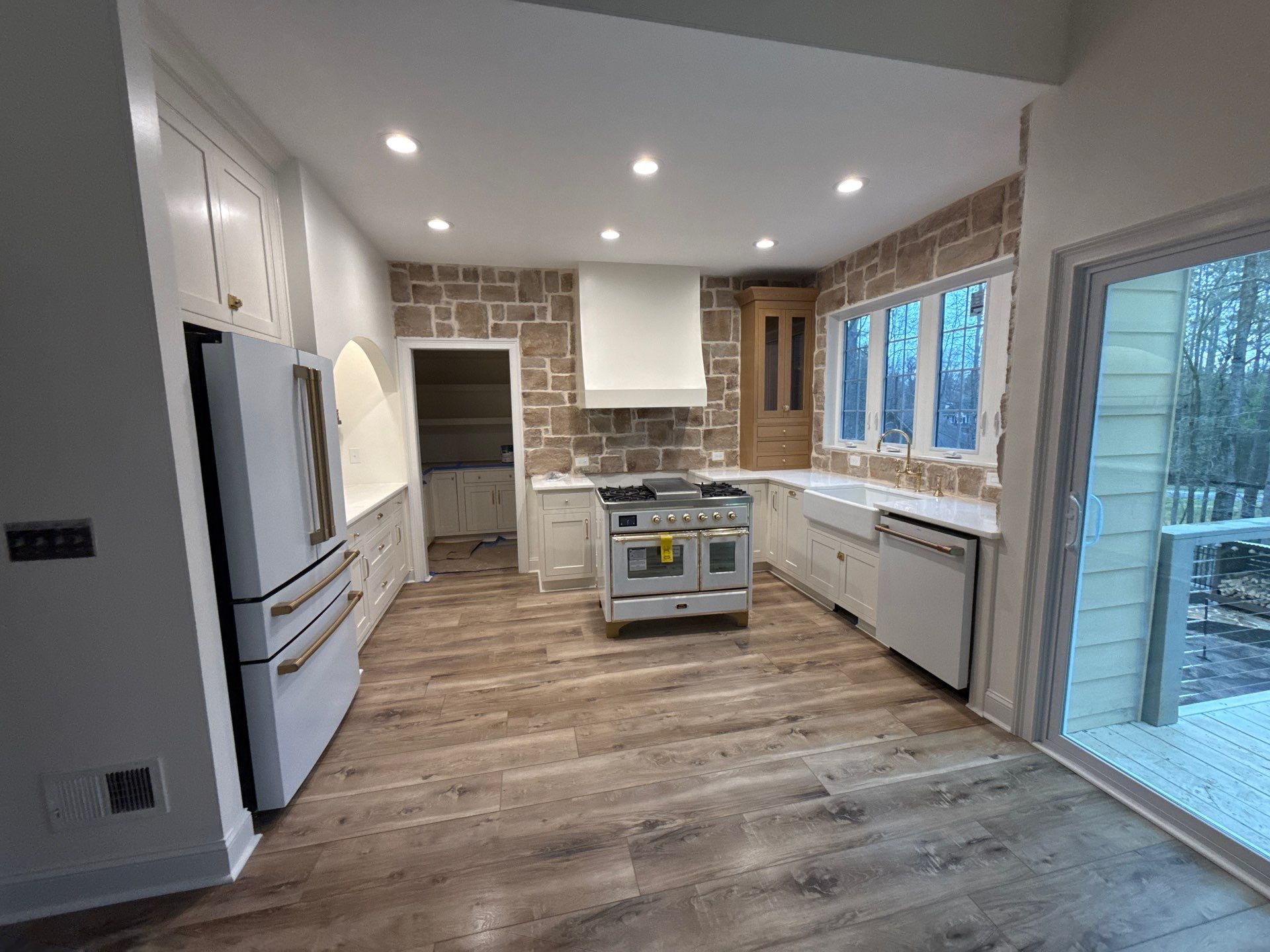 Kitchen renovation completed โ white shaker cabinets, stone accent wall, professional dual-oven range, farmhouse sink, new hardwood floors โ Powder Springs, GA, Estate Solutions