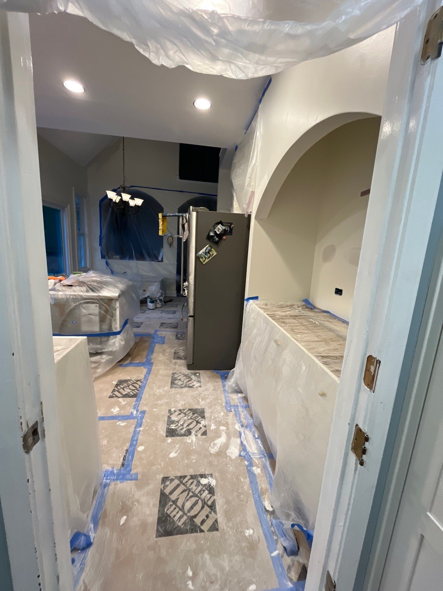 Kitchen renovation during paint prep โ plastic sheeting over surfaces, drywall work in progress, arched entry โ Powder Springs, GA, Estate Solutions