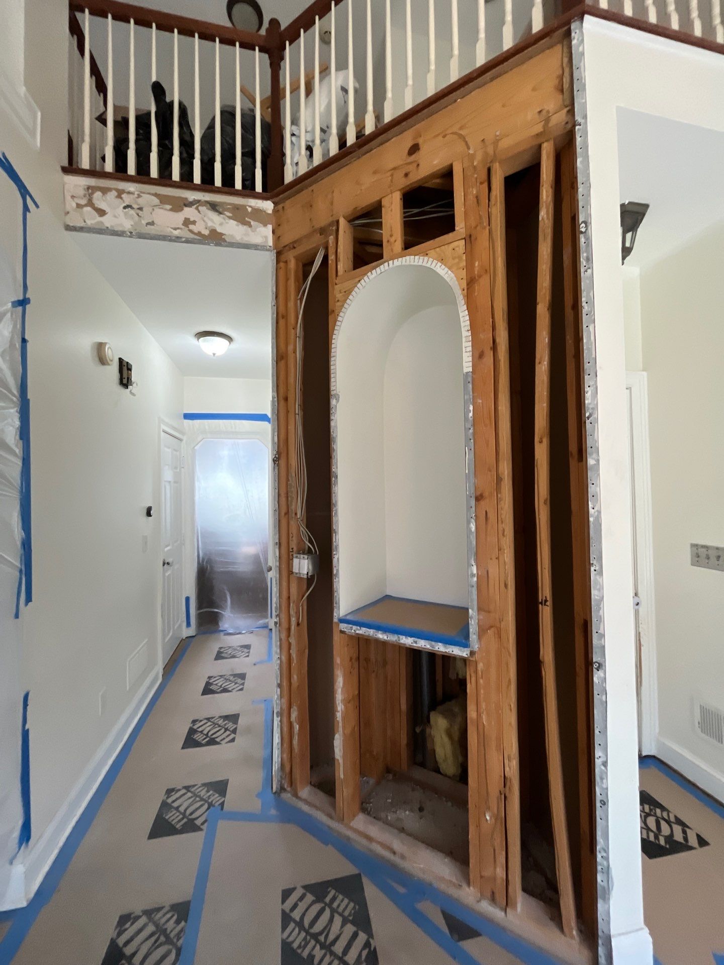 Kitchen demo phase โ wall framing exposed for new arched opening construction, staircase and balcony visible, floors protected โ Powder Springs, GA, Estate Solutions