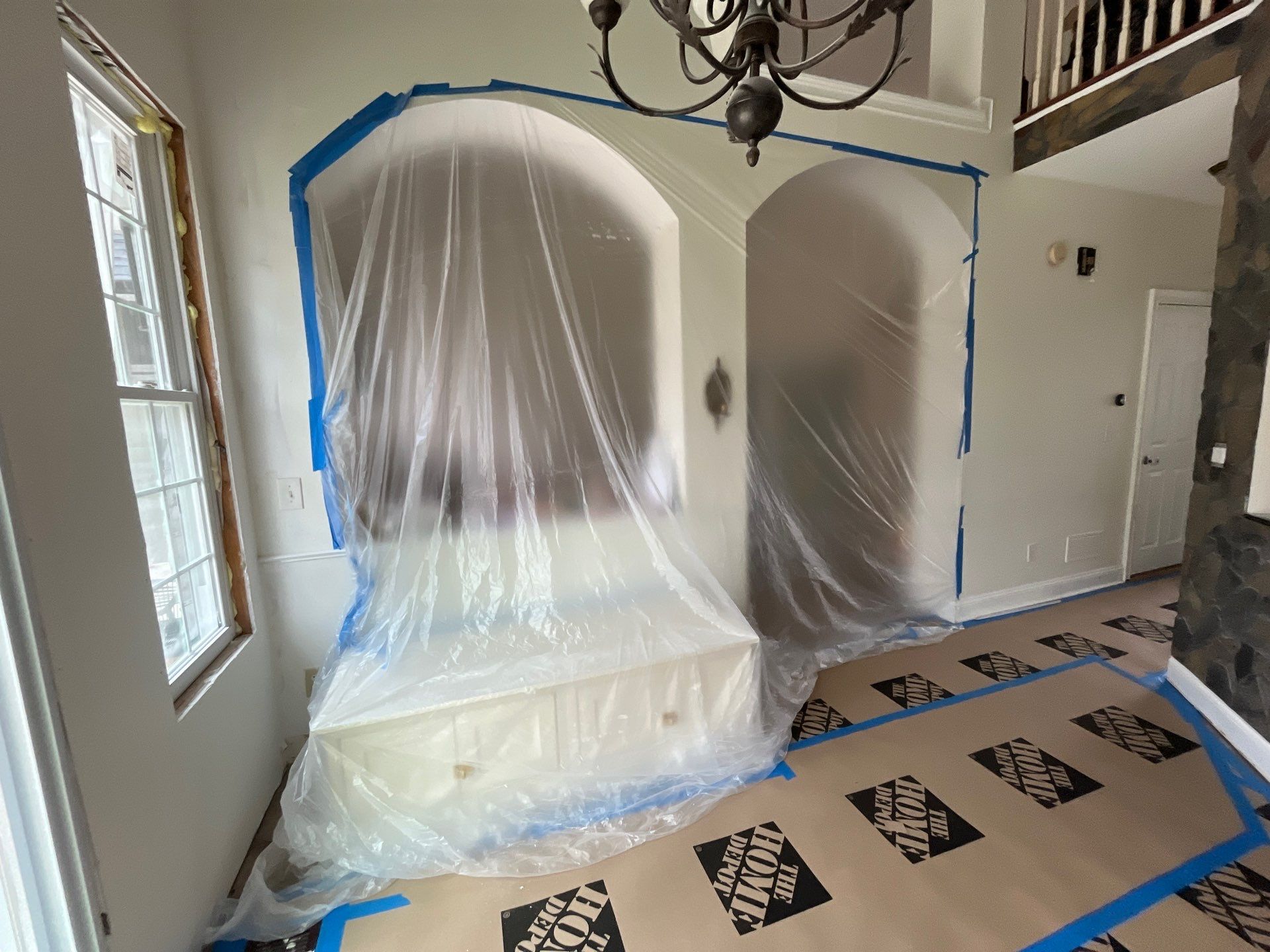 Dining area during renovation โ new chandelier installed, arched openings prepped and protected, floors covered โ Powder Springs, GA, Estate Solutions