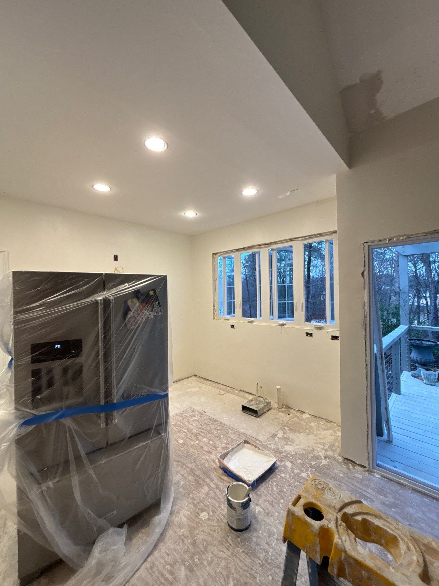Kitchen renovation during construction โ new recessed lighting, refrigerator wrapped, wide windows roughed in, deck door opening โ Powder Springs, GA, Estate Solutions
