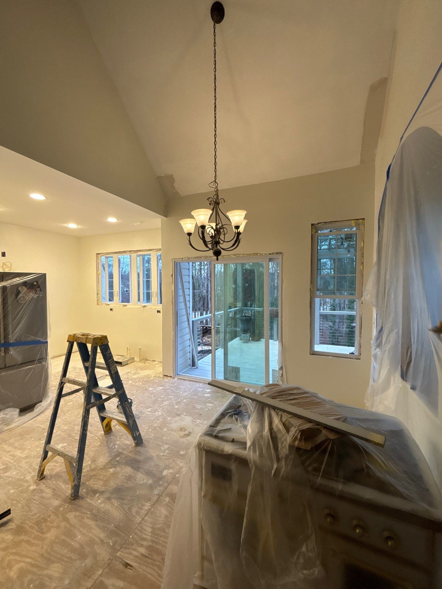 Open kitchen and dining area during renovation โ vaulted ceiling, new chandelier, sliding glass door to deck roughed in ๏ฟฝ๏ฟฝโ Powder Springs, GA, Estate Solutions