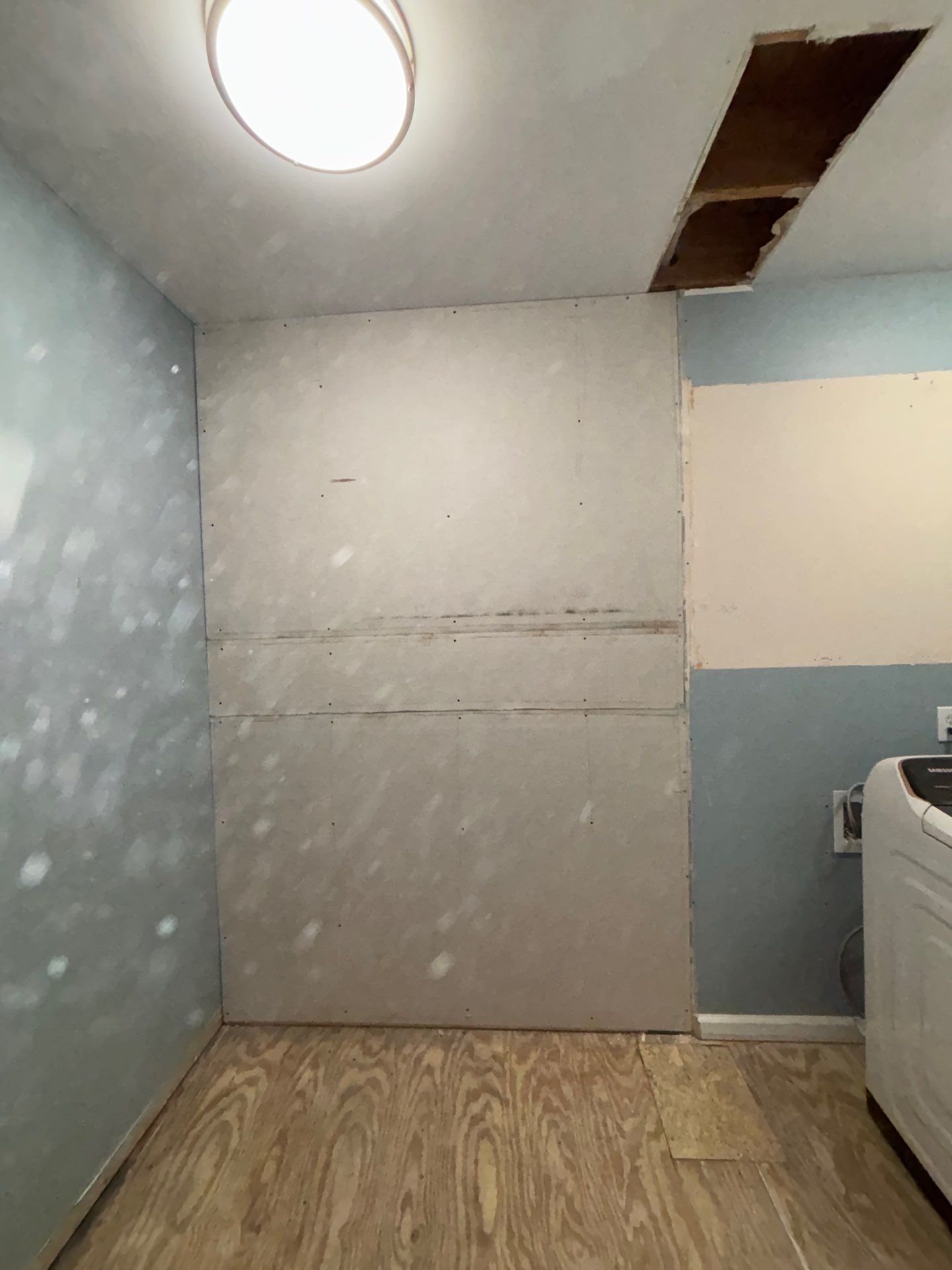 Laundry room during renovation โ new drywall installed on wall, ceiling opened for rough-in, subfloor exposed โ Powder Springs, GA, Estate Solutions