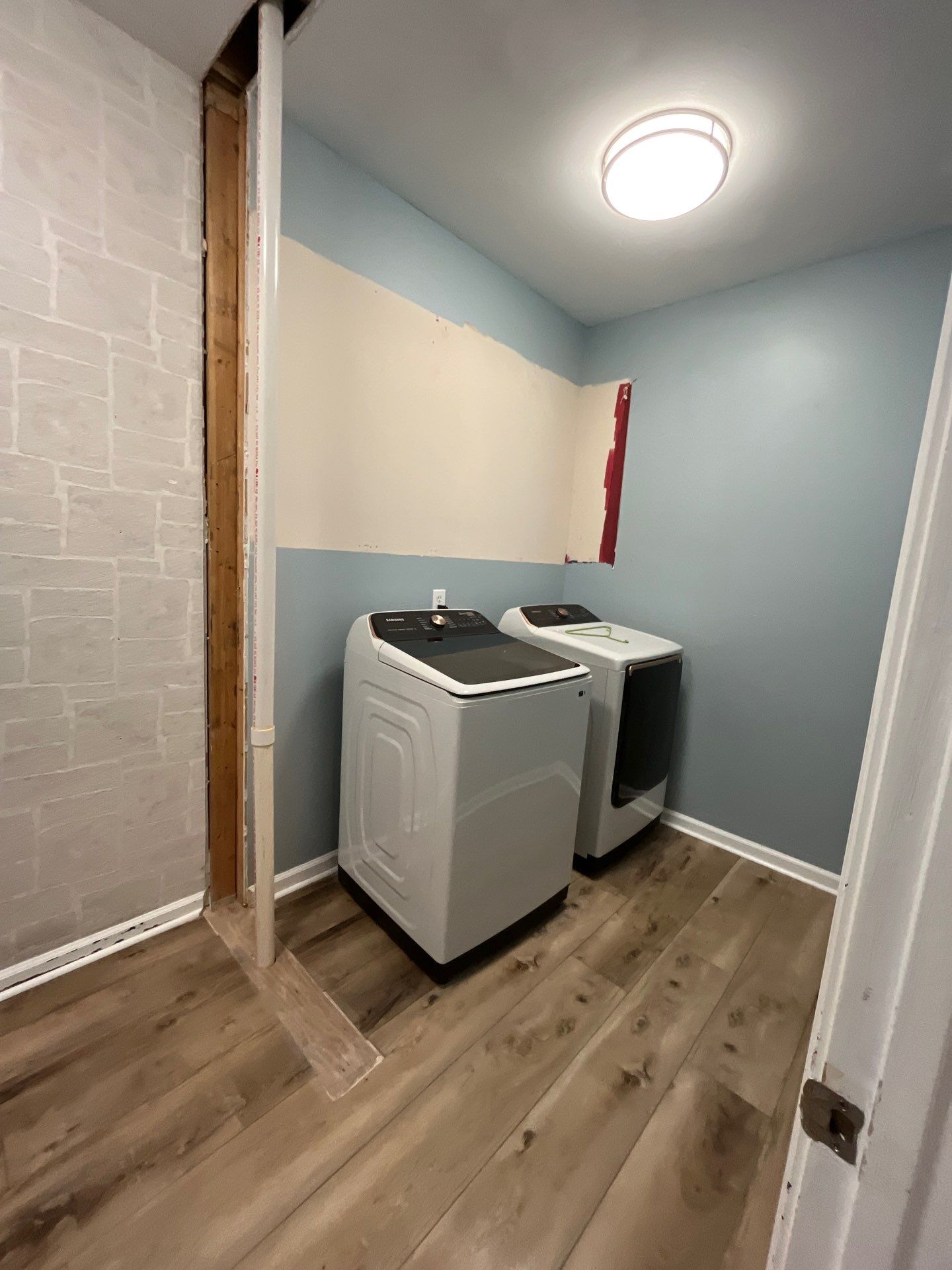 Laundry room renovation complete โ new washer and dryer, LVP hardwood floors, blue painted walls, painted brick accent wall โ Powder Springs, GA, Estate Solutions