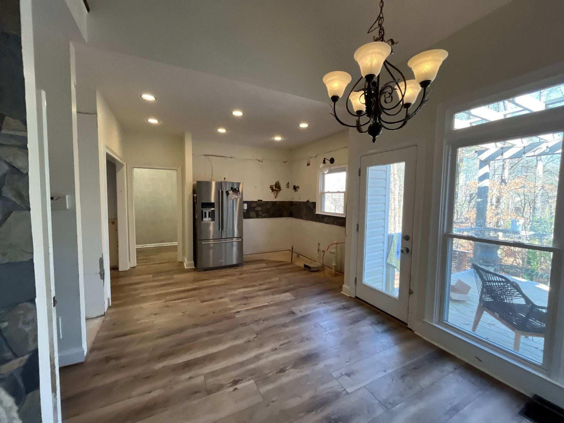 Open concept kitchen and dining area after new flooring โ LVP hardwood installed, stone accent wall, sliding glass door to deck โ Powder Springs, GA, Estate Solutions
